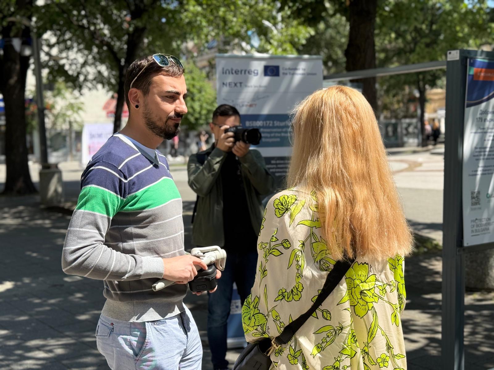Мъж дава интервю пред камера на открито